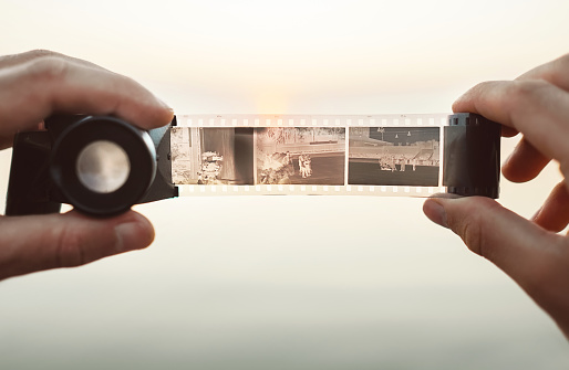 Imagen de manos de hombre usando la película vintage 35mm negativos Viewer para ver capítulos sobre el fondo del atardecer photo