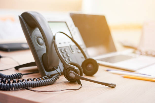 close up focus on call center headset device at telephone VOIP system at office desk for hotline telemarketing concept with vintage color filter close up focus on call center headset device at telephone VOIP system at office desk for hotline telemarketing concept with vintage color filter voip stock pictures, royalty-free photos & images