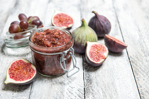 Figs jam in jar. Fruit marmalade on rustic wooden background