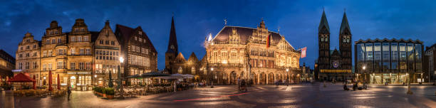 Panorama shot of Bremen market square with guildhall, cathedral and parliament (Rathaus, Dom und Bürgerschaft). Moody twilight at dusk. Illuminated Buildings. Germany - Europe
