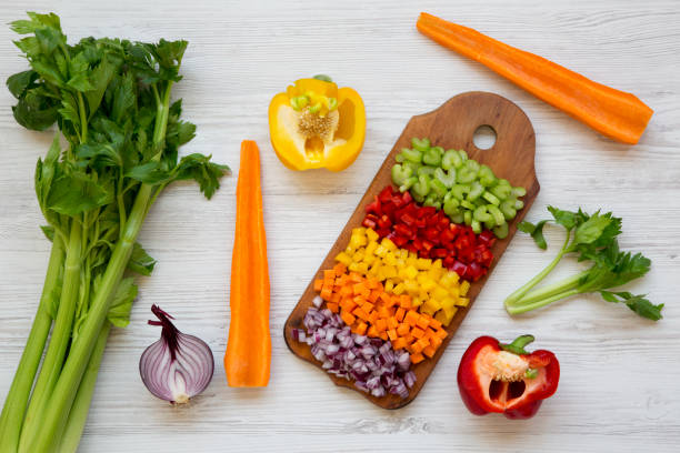istock Chopped fresh vegetables (carrot, celery, red onion, peppers) arranged on cutting board on white wooden table, top view. From above, overhead, flat lay. 1030021686