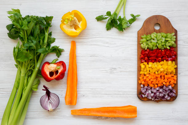 istock Chopped fresh vegetables (carrot, celery, red onion, peppers) arranged on cutting board on white wooden table, top view. From above, overhead, flat lay. Space for text. 1030021804