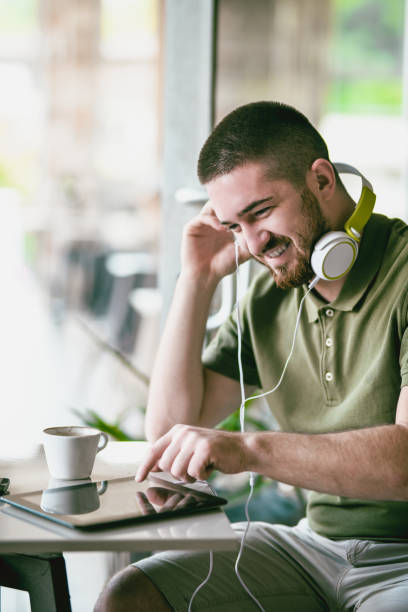 istock Smiling Male Listening To Music On Tablet While Drinking Coffee 1030027356