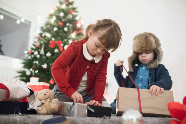 istock Children trying to unwrap their presents 1030039574