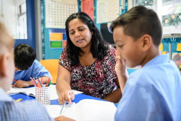 Photo of Aboriginal primary school teacher helping young boy in the classroom