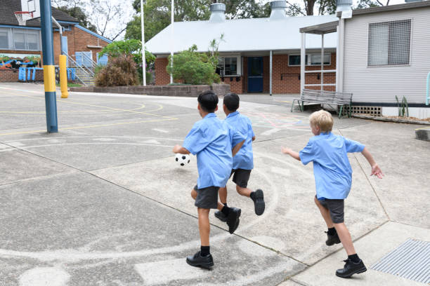 istock Three school boys playing in school yard with football 1030071474