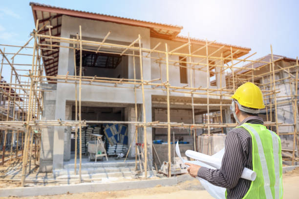 istock Professional engineer architect worker with protective helmet and blueprints paper at house building construction site 1030071730