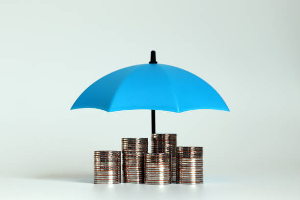 A pile of coins with an open blue umbrella. stock photo