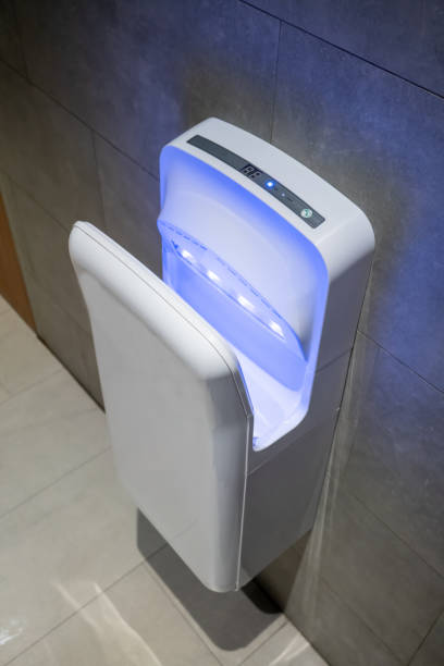 istock Modern vertical hand dryer hanging on wall in public restroom WC 1030092784