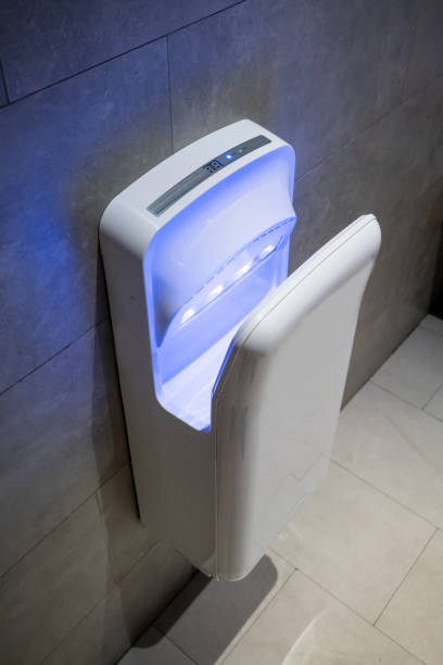 istock Modern vertical hand dryer hanging on wall in public restroom WC 1030092794
