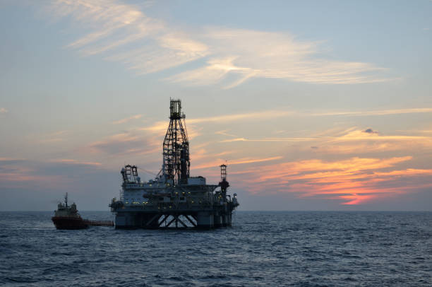 plataforma de petróleo semi-submersível com uma nave de abastecimento em crepúsculo - oil rig sea oil well oil drill - fotografias e filmes do acervo