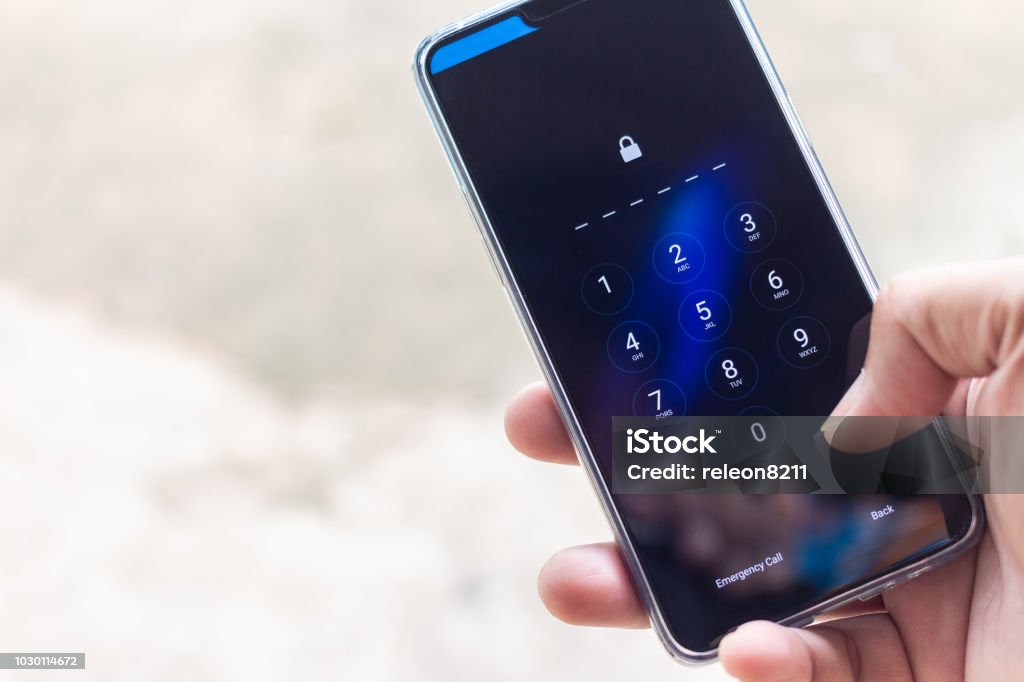 Hand holding smartphone while entering the passcode. Telephone Stock Photo
