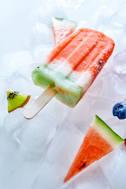 istock Frozen natural vanilla watermelon smoothies on a stick on ice cubes. Ice lolly. Top view 1030163550