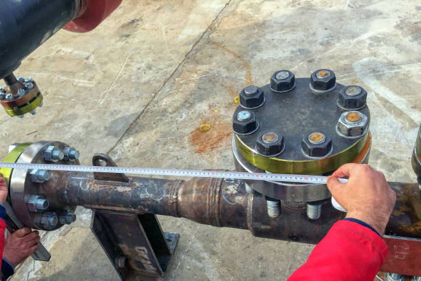 istock Dimensions control of the process piping ( pipeline ) with a tape measure. The process or set of processes used to measure and assure the quality of a product and quality control. The process of ensuring products and services. 1030181858