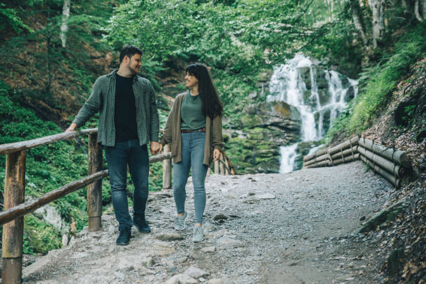 istock couple walk holding hands. waterfall on background. 1030195720