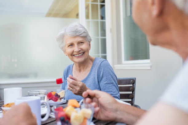 年配のカップル朝食 - women eating fruit food ストックフォトと画像
