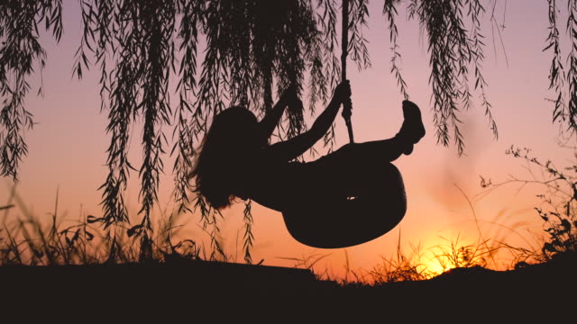 Happy laughing child girl on swing in sunset summer video