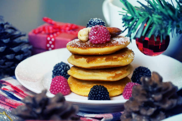 istock Pancake topping with berries and nut with background gift and pine cone under christmas tree, holiday party dessert. 1030218026