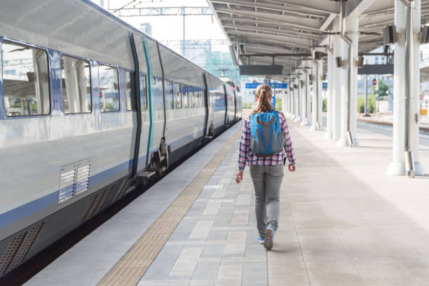 istock Young woman walking along platform to catch train. Rail travel 1030218312