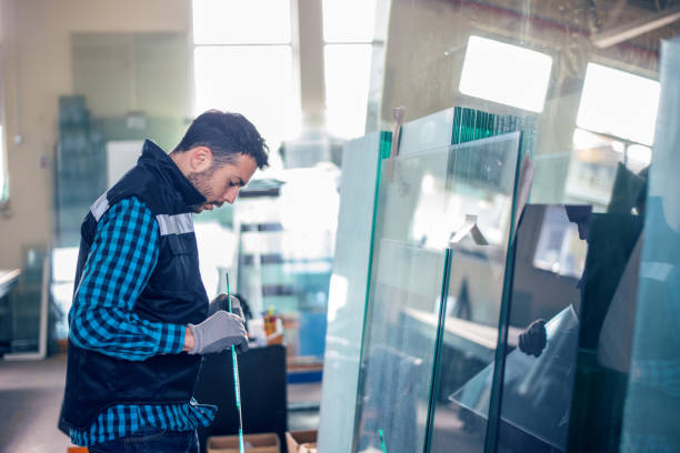 Worker handling glass sheet in warehouse