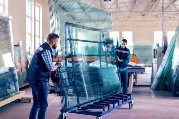 lavoratori che confezionano lastre di vetro in magazzino - glass factory foto e immagini stock