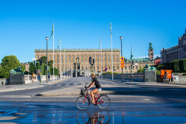 Stockholm, Sweden - 8/5/2018, 6:10:36 PM: Scandinavian woman on bike. Scene from Gamla stan in central Stockholm. Traffic in background.