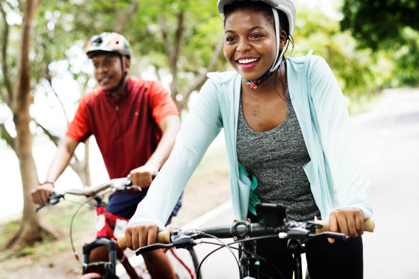 pareja de ciclistas viajan juntos en un parque - andar en bicicleta fotografías e imágenes de stock