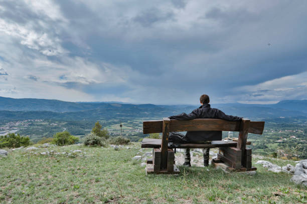 istock Young Adult Man Looking at View From a Bench 1030240212