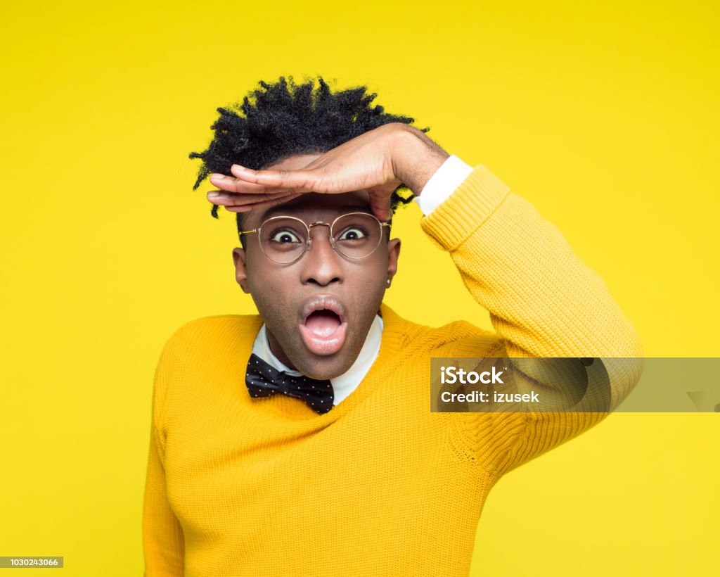 Funny portrait of surprised young man smiling at camera Funny portrait of excited nerdy young afro American man wearing yellow sweater and black bow tie staring at camera. Men Stock Photo
