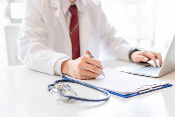 istock Male doctor working on desk with laptop. 1030246806