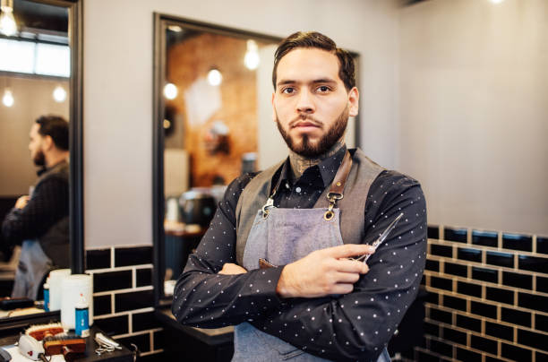 istock Confident male barber holding scissors in salon 1030250016