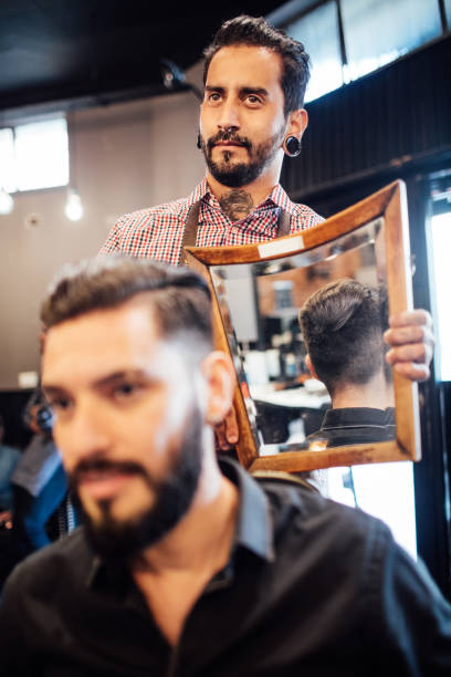 istock Client looking at haircut in mirror held by barber 1030253738