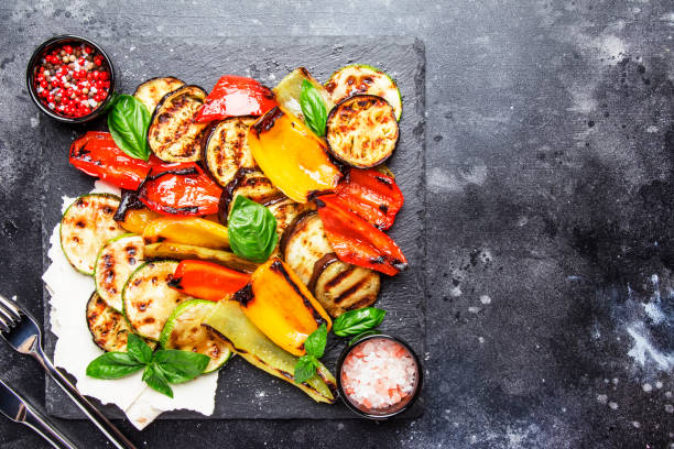 verdure multicolori grigliate, melanzane, zucchine, pepe con basilico verde su tavola di pietra da portata - grilled vegetable eggplant zucchini foto e immagini stock