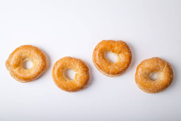 istock Four fresh baked bagle buns with sesame seeds on white background pre-cut for making sandwiches 1030267012
