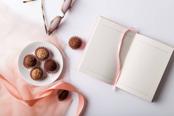 istock Variety of chocolate truffles and open empty notebook on white background 1030267156