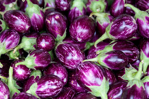 Stack of small eggplants on a market stall.