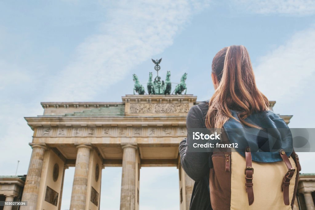 A tourist girl with a backpack looking at the Brandenburg Gate in Berlin A tourist girl with a backpack or student looking at the Brandenburg Gate in Berlin in Germany. Germany Stock Photo