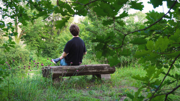 istock Young Man Sitting on Wood Park Bench 1030274260