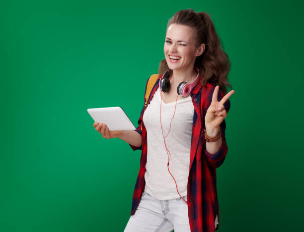 istock student woman with tablet PC showing victory isolated on green 1030274368