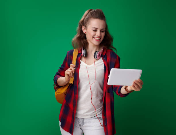 istock smiling young student woman using tablet PC on green background 1030274418