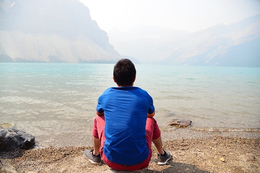 A man sitting by Lake Louise, enjoying the beautiful view and sunny weather.