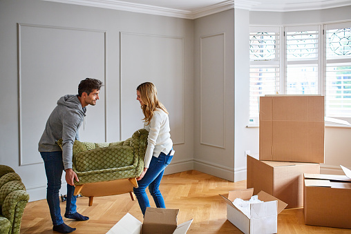 Shot of a happy young couple moving furniture in their new house