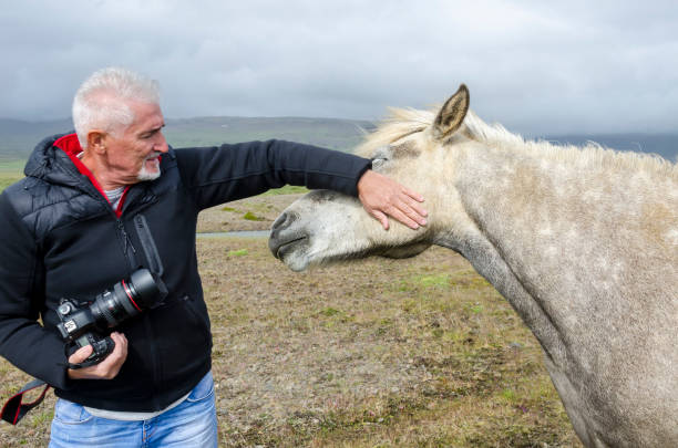 istock naturalist photographer caressing a spotted horse 1030284020