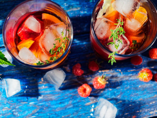 Lemonade with raspberry, peach and thyme Ice lemonade with raspberry, peach and thyme on the table under raspberry bush sangria stock pictures, royalty-free photos & images