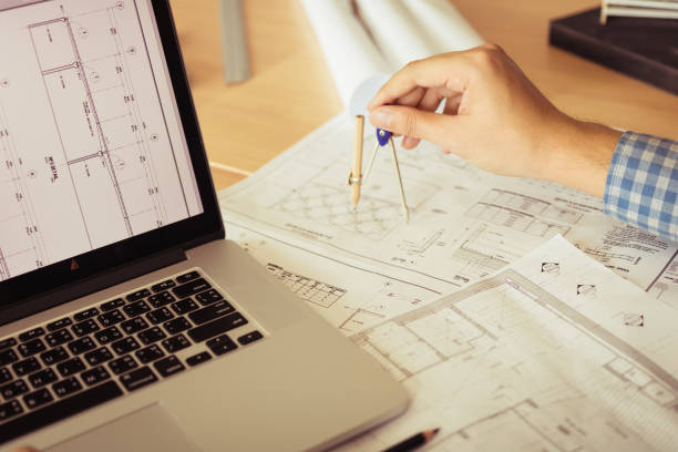 l’architecte travaillant sur le plan d’action en milieu de travail avec ordinateur portable et compas de dessin. - drawing compass architect blueprint planning photos et images de collection