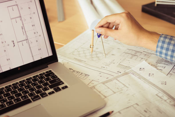 Architect working on blueprint in workplace with laptop and drawing compass. Architect working on blueprint in workplace with laptop and drawing compass. autocad house plans stock pictures, royalty-free photos & images
