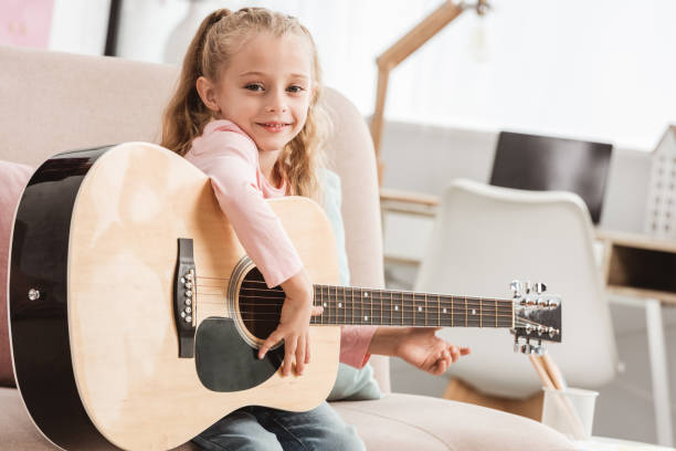 istock smiling kid playing on guitar at home 1030294378