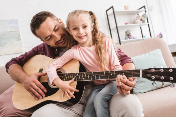 istock dad and daughter having fun and playing on guitar 1030294386