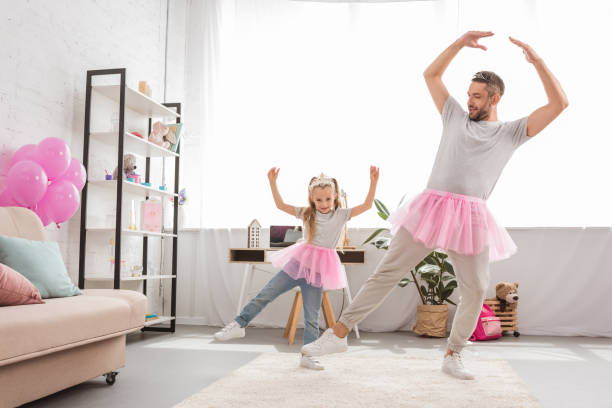 funny father and daughter in pink tutu skirts dancing like ballerinas - pai e filha a dançar imagens e fotografias de stock