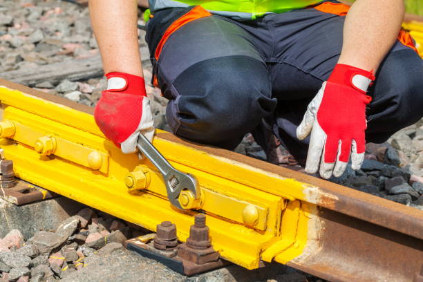 istock Worker with adjustable wrench fixing screw nut on railway track 1030298748